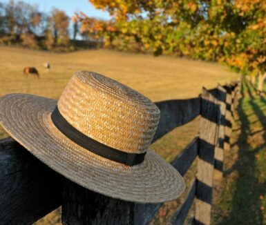 Closeup of traditional Amish straw hat in front of horse farm in the fall | Lancaster County Amish Experience in Lancaster PA