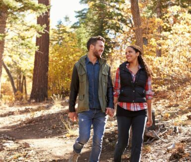 Couple hiking in a forest hold hands and look at each other and discovering the outdoor activities in York, PA