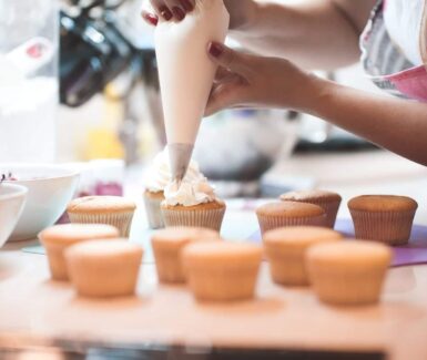 close up of hand putting white icing on scratch cupcakes in ephrata, PA